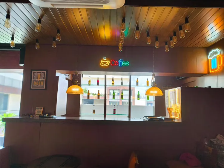 Bar counter with backlit bottle shelves and hanging lamps