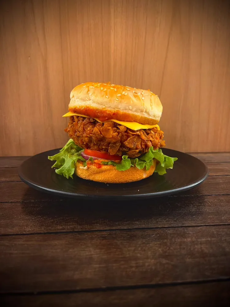 A fried chicken burger on a black plate