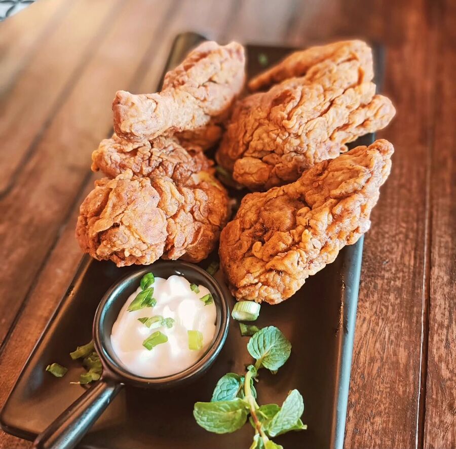 Crispy fried chicken with a yoghurt dip on a dark platter