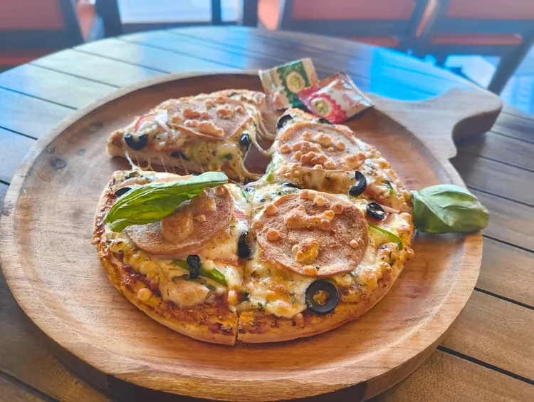Wood-plated veg pizza with olives and capsicum
