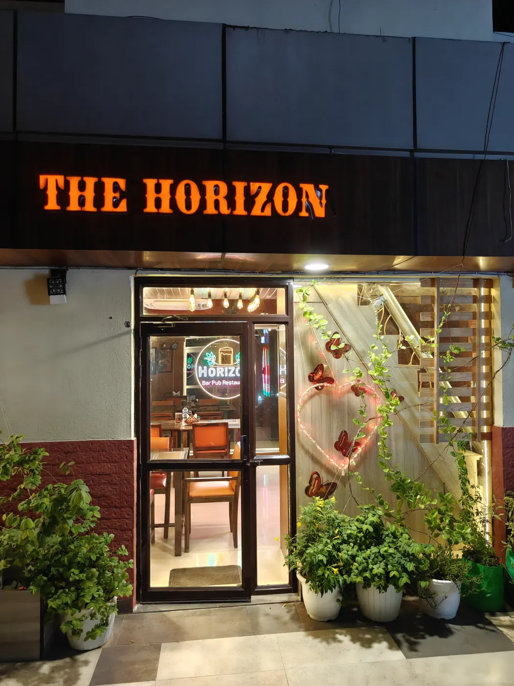 The entrance framed by plants, with The Horizon sign above