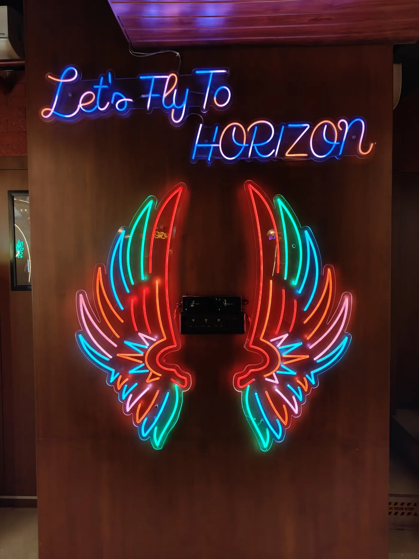 The Let's Fly To Horizon neon wings wall
